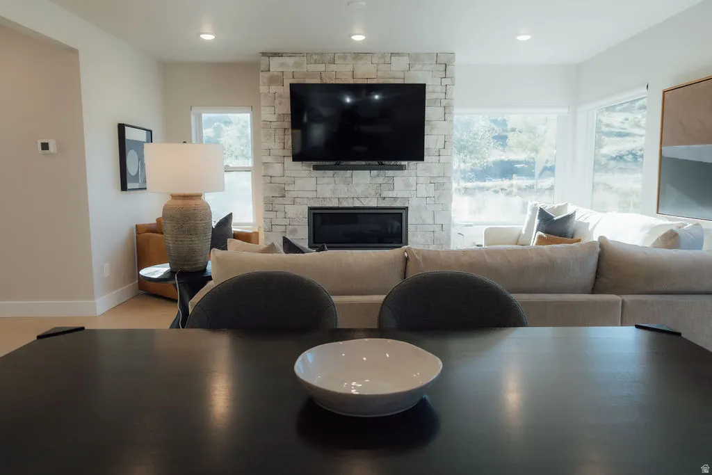 Open-concept living space featuring a stone-clad fireplace and large windows