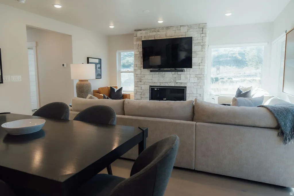 Open concept living space featuring a stone-clad fireplace with built-in hearth, recessed lighting, and large windows