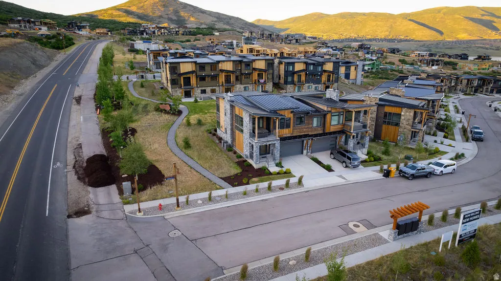 Contemporary architecture featuring stone and wood-look siding, multiple balconies, and a two-car garage