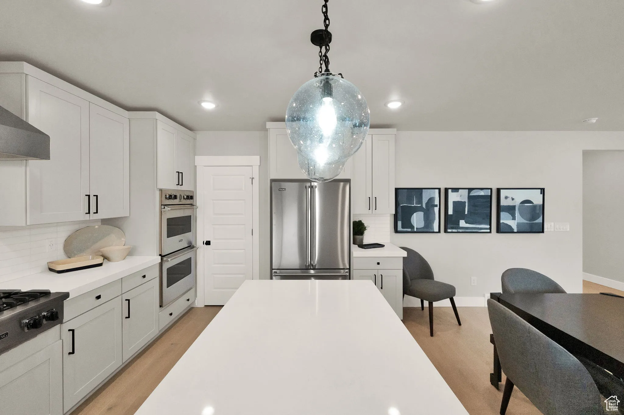 Kitchen with appliances with stainless steel finishes, light wood finished floors, backsplash, light countertops, and recessed lighting