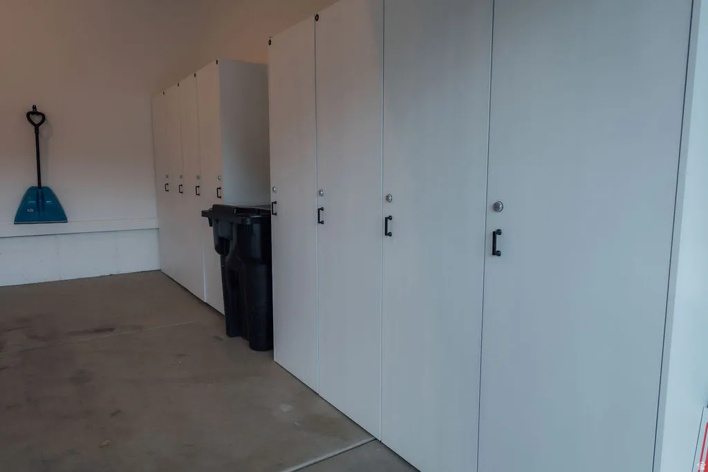 Built-in white storage cabinetry featuring black hardware and integrated locks, set against a light-colored wall