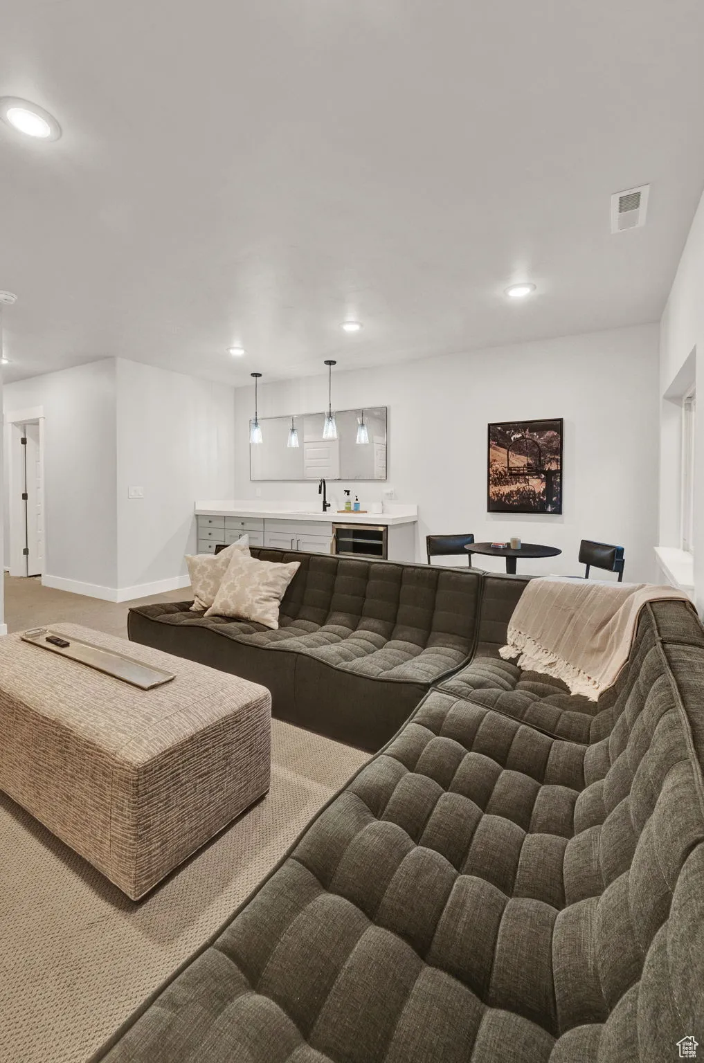 Carpeted living area featuring recessed lighting, baseboards, and bar