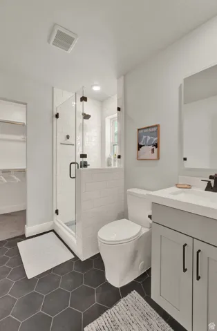 Full bathroom with vanity, a shower stall, toilet, tile patterned flooring, and a walk in closet