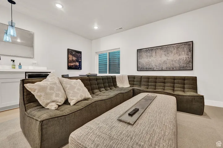 Living room with recessed lighting, bar area, light carpet, and baseboards