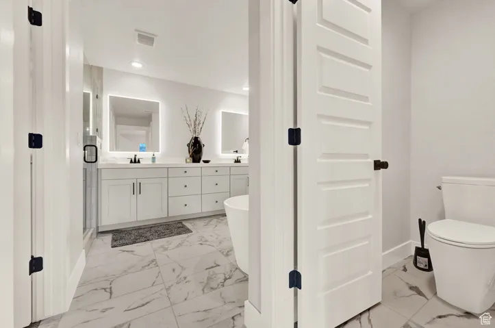 Full bath with marble finish floors, baseboards, double vanity, toilet, and recessed lighting