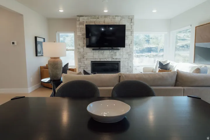 Open-concept living space featuring a stone-clad fireplace and large windows