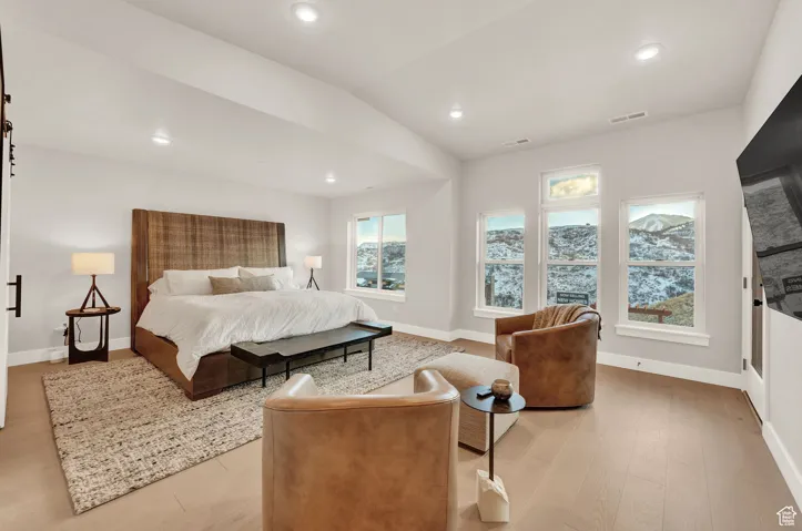 Bedroom with light wood finished floors, baseboards, recessed lighting, and lofted ceiling