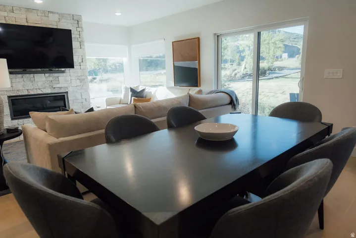 Open-concept living area featuring a stone-clad fireplace, built-in television mount, and expansive sliding glass doors