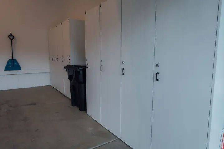 Built-in white storage cabinetry featuring black hardware and integrated locks, set against a light-colored wall