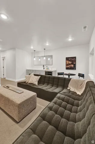 Carpeted living area featuring recessed lighting, baseboards, and bar