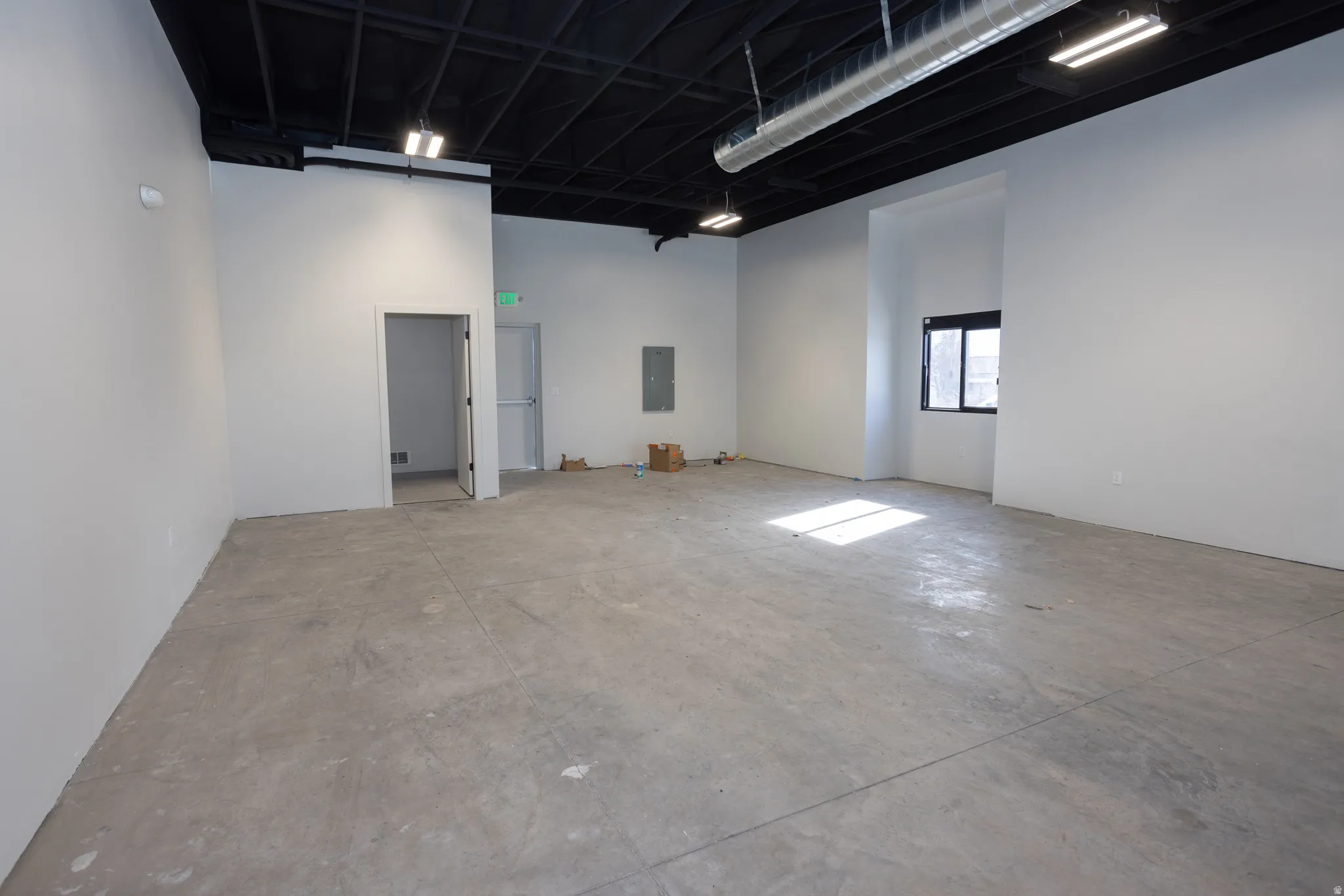 Spare room featuring a high ceiling, unfinished concrete flooring, and electric panel