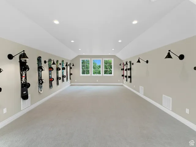 Above garage living room featuring carpet floors, vaulted ceiling, baseboards, and recessed lighting