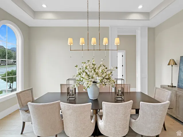 Dining space featuring plenty of natural light, light wood finished floors, a tray ceiling, recessed lighting, and baseboards