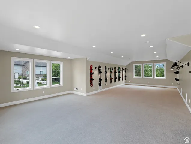 Above garage living room featuring carpet floors, vaulted ceiling, baseboards, and recessed lighting