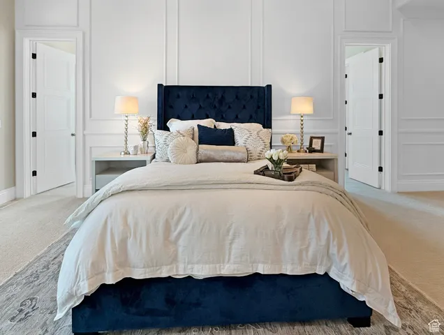 Bedroom featuring a decorative wall, carpet flooring, and baseboards