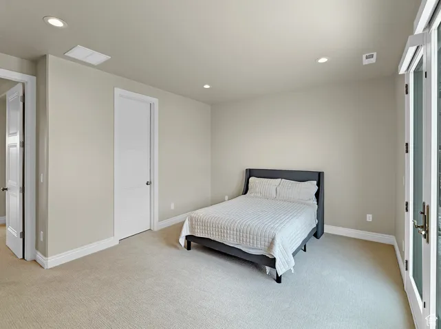 Bedroom with light colored carpet, recessed lighting, and baseboards