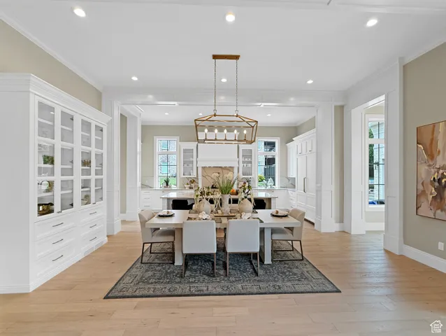 Dining area with ornamental molding, light wood-type flooring, recessed lighting, baseboards, and a chandelier