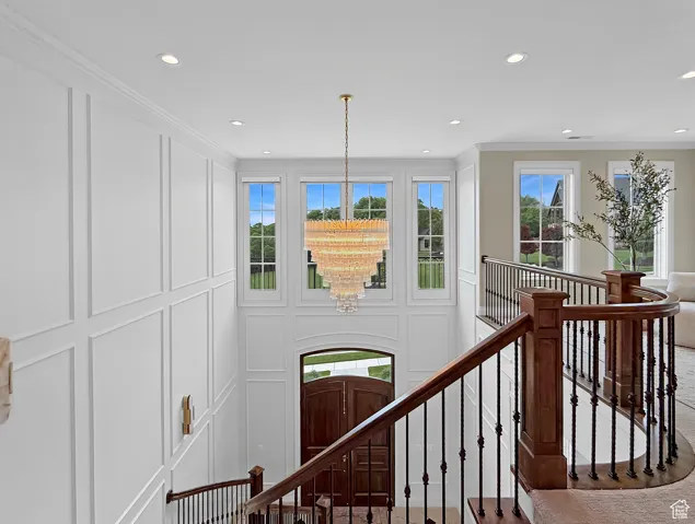 Stairs featuring a decorative wall, recessed lighting, crown molding, and a chandelier