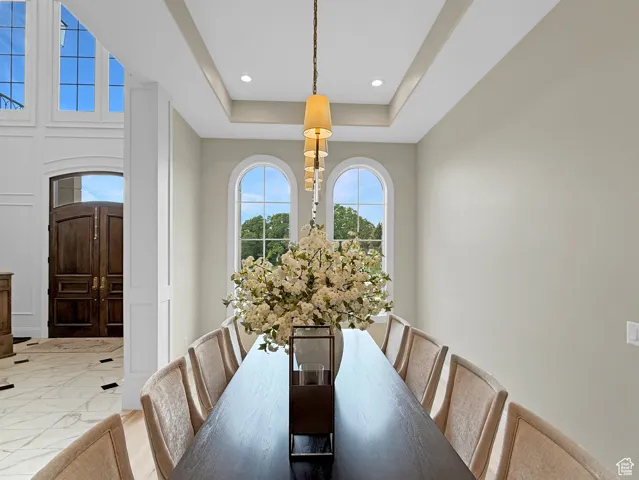 Dining space with marble finish flooring, recessed lighting, and a tray ceiling