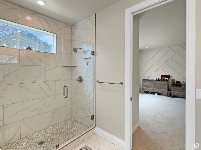 Bathroom with a shower stall, marble look tiles, baseboards, and recessed lighting