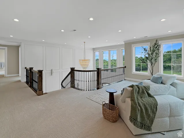 Sitting room with an upstairs landing, light colored carpet, recessed lighting, baseboards, and crown molding