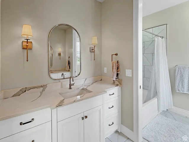 Bathroom featuring marble finish floors, vanity, baseboards, and shower / bath combination with curtain