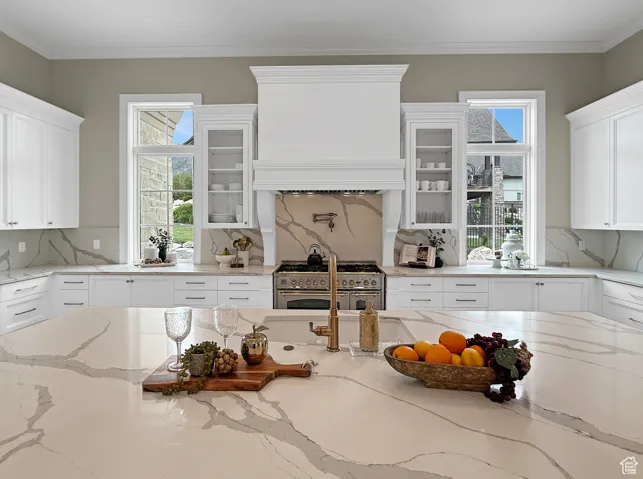 Kitchen featuring range. white cabinets, decorative backsplash, and crown molding