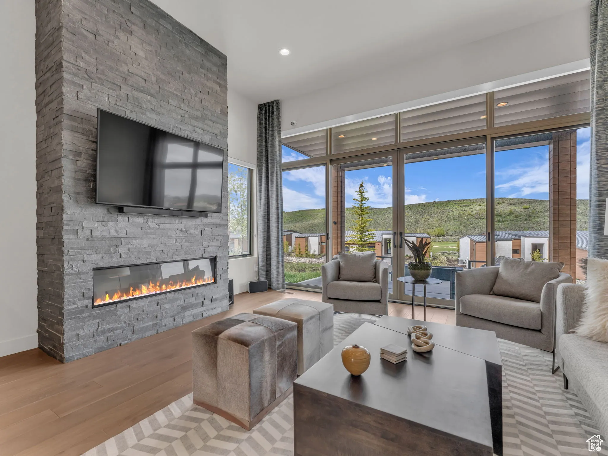 Living area featuring a stone fireplace, wood finished floors, recessed lighting, abundant natural light