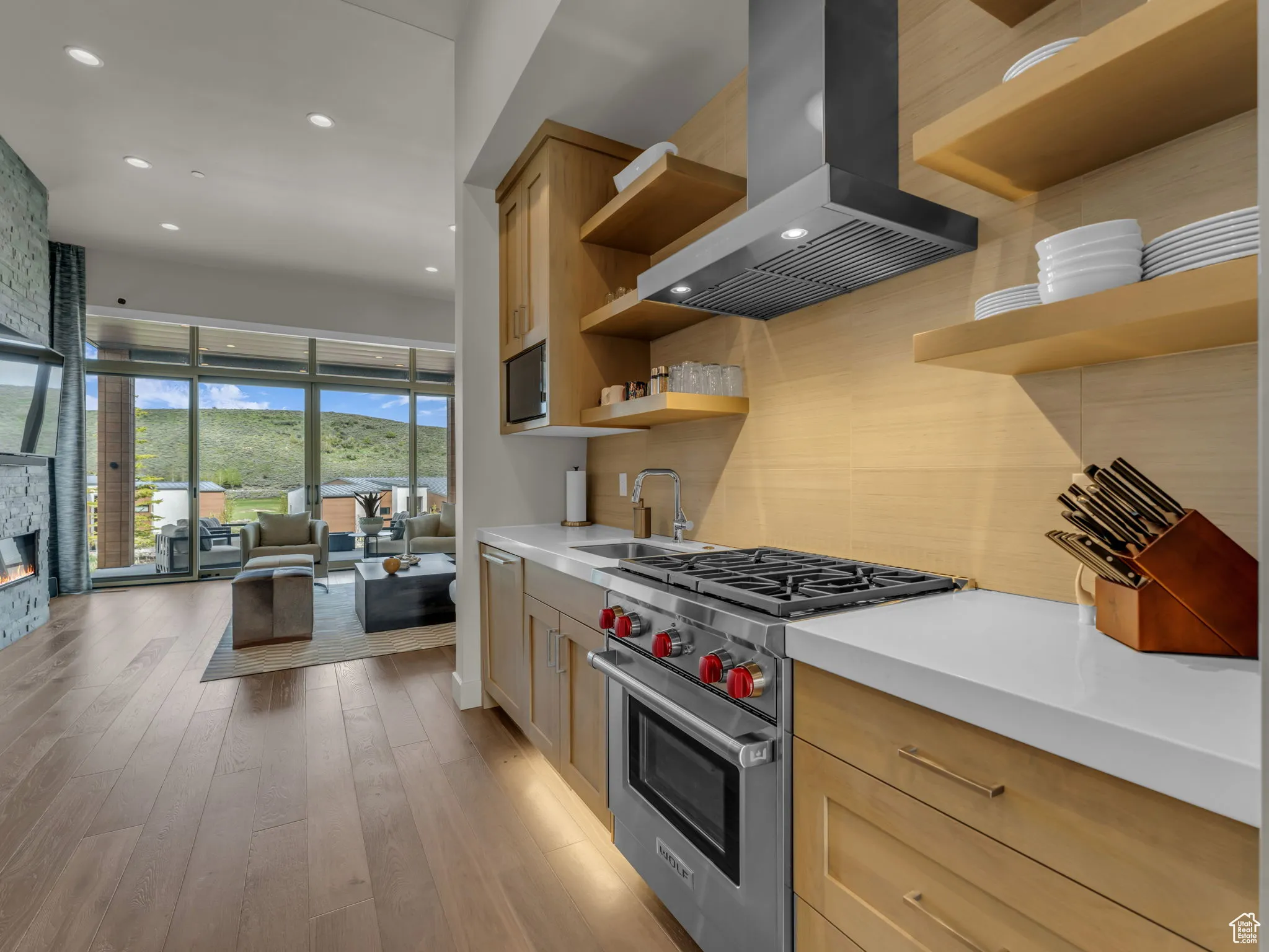 Kitchen with open shelves, designer stove, a sink, microwave, chimney exhaust hood, and backsplash
