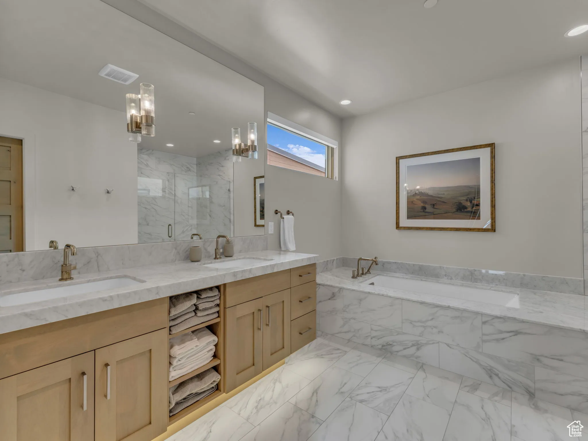 Bathroom featuring a bath, double vanity, a marble finish shower, marble finish floors, and a chandelier