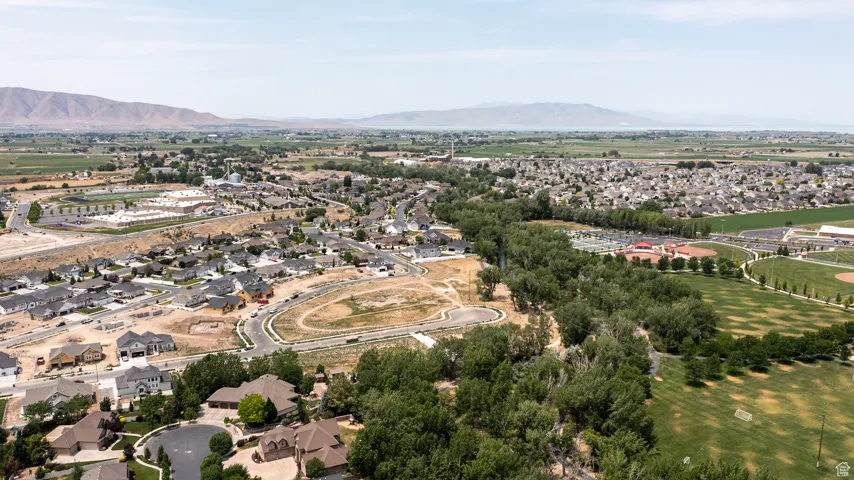 Aerial view of property and surrounding area featuring a mountainous background and nearby suburban area