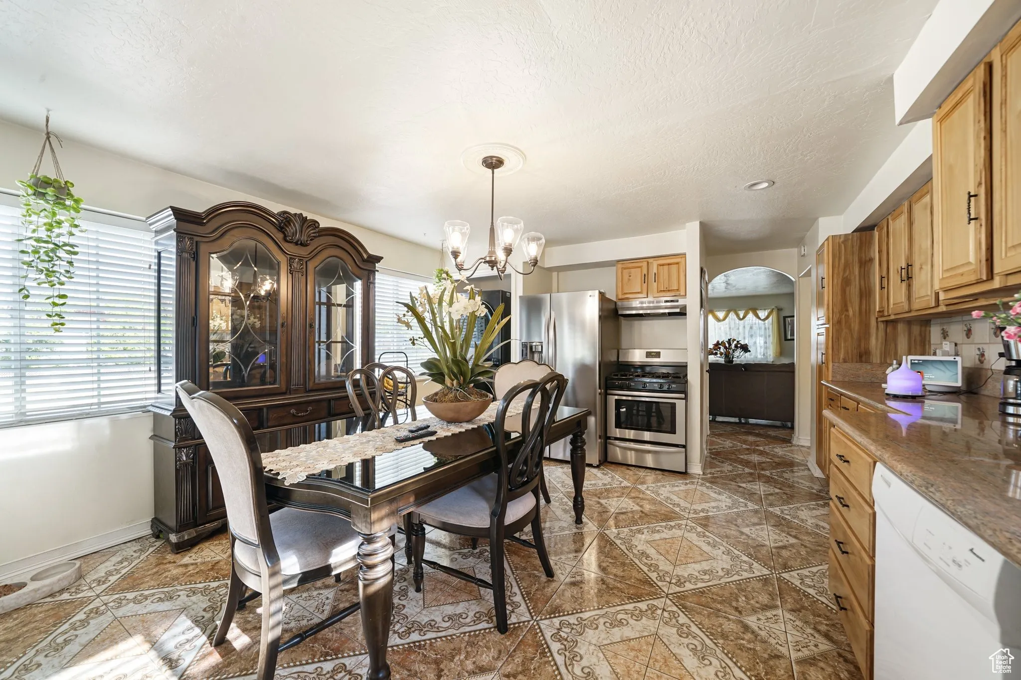 Tiled dining room featuring arched walkways, a chandelier, baseboards, and a textured ceiling