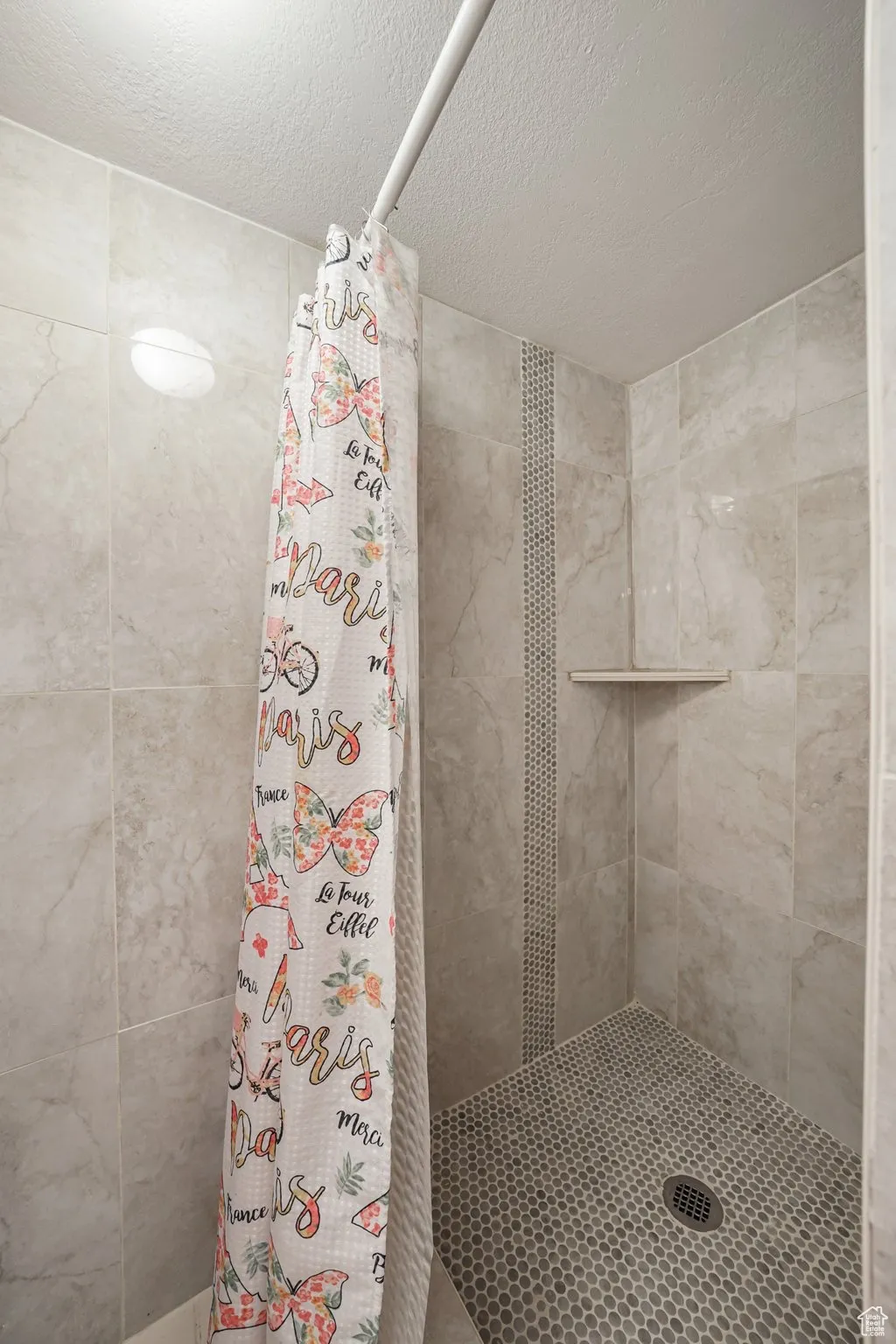 Full bath featuring a stall shower and a textured ceiling