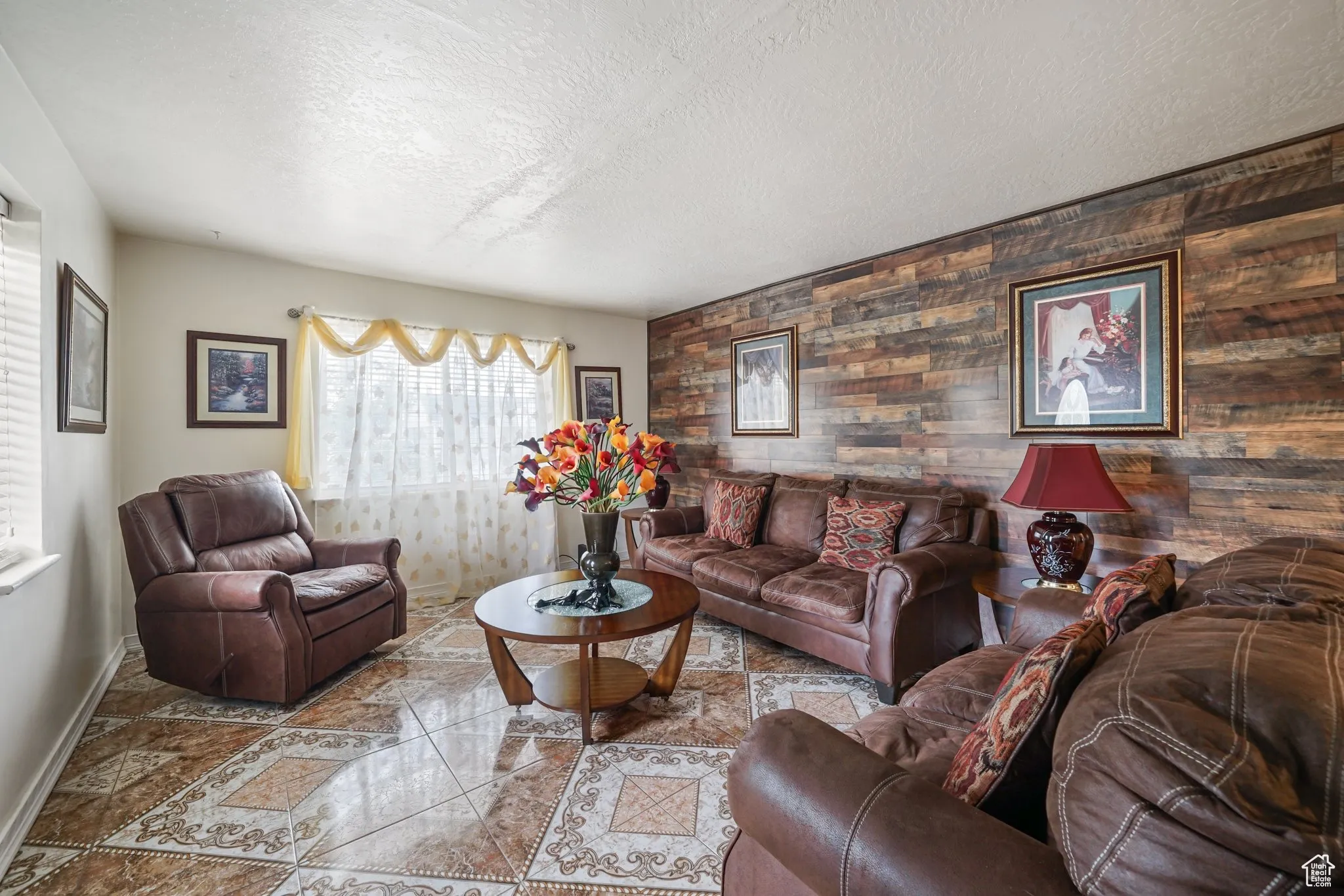 Living room with a textured ceiling, baseboards, and wood walls