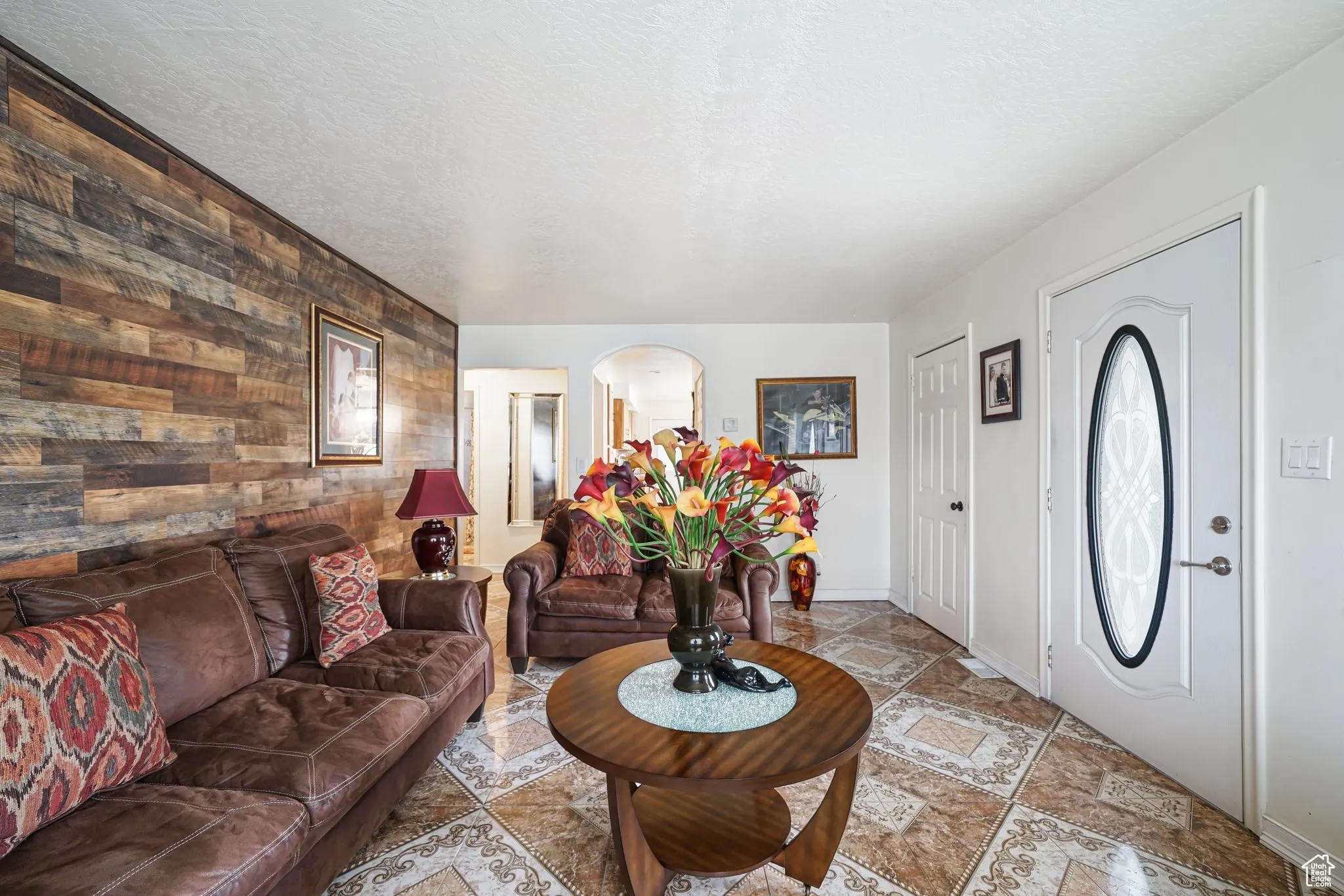 Foyer with wooden walls, an accent wall, arched walkways, baseboards, and light stone finish flooring