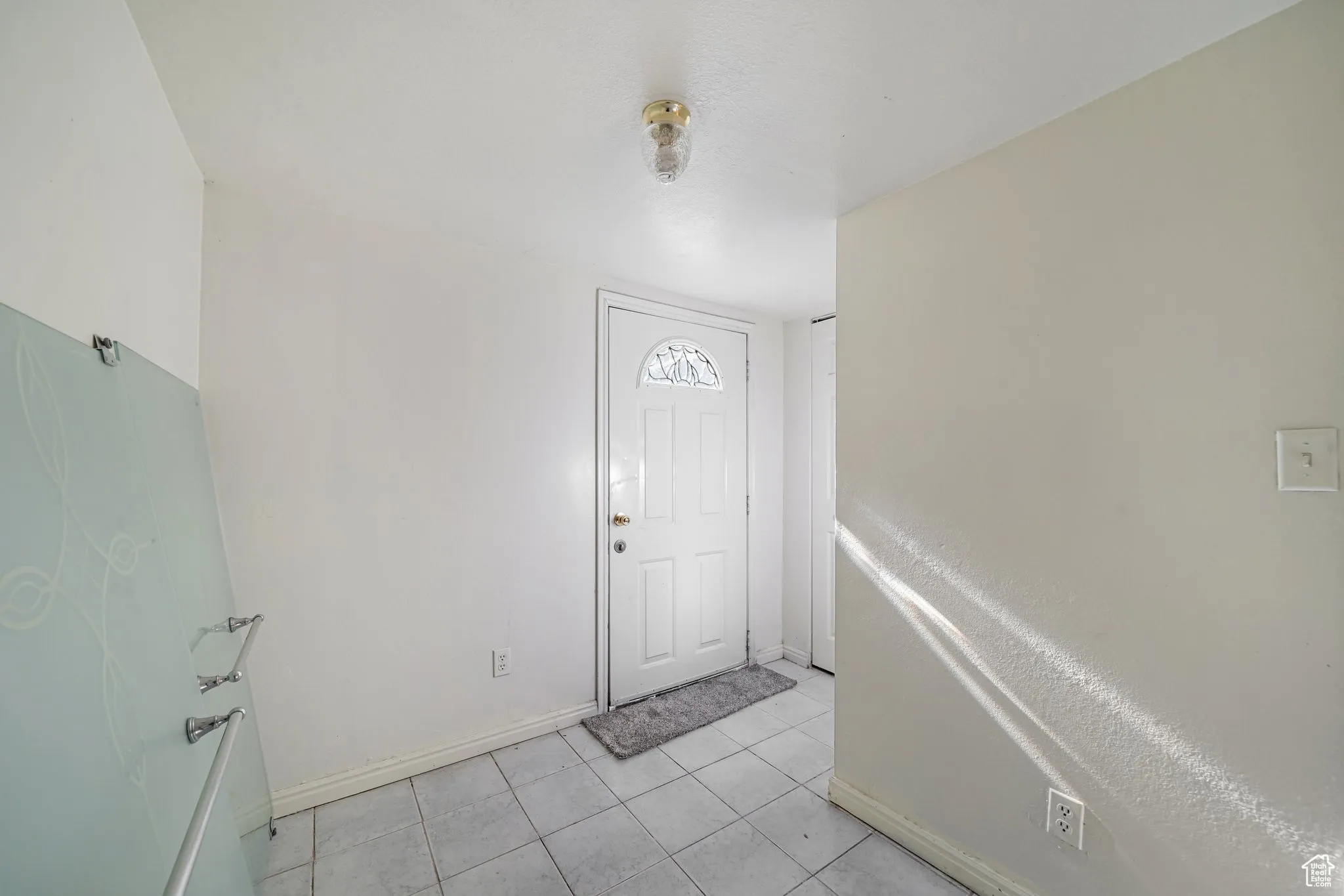 Foyer entrance with light tile patterned floors and baseboards