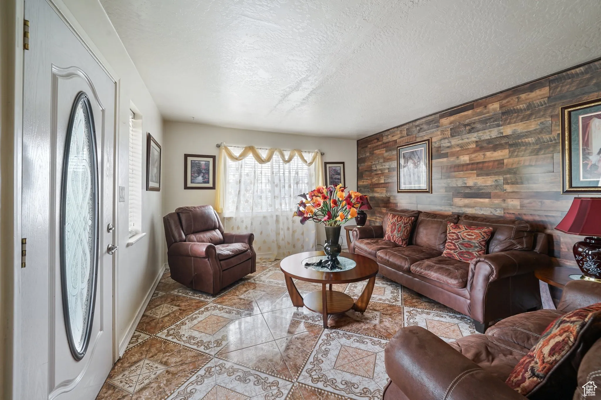 Tiled living room with wood walls, baseboards, and a textured ceiling