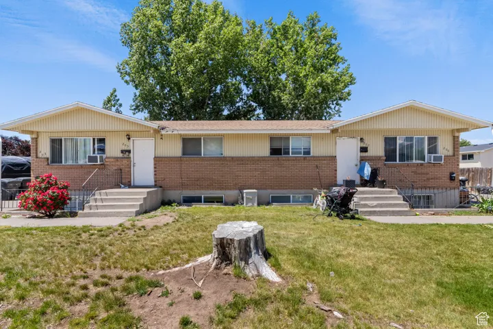 Single story home with brick siding, a front yard, and cooling unit