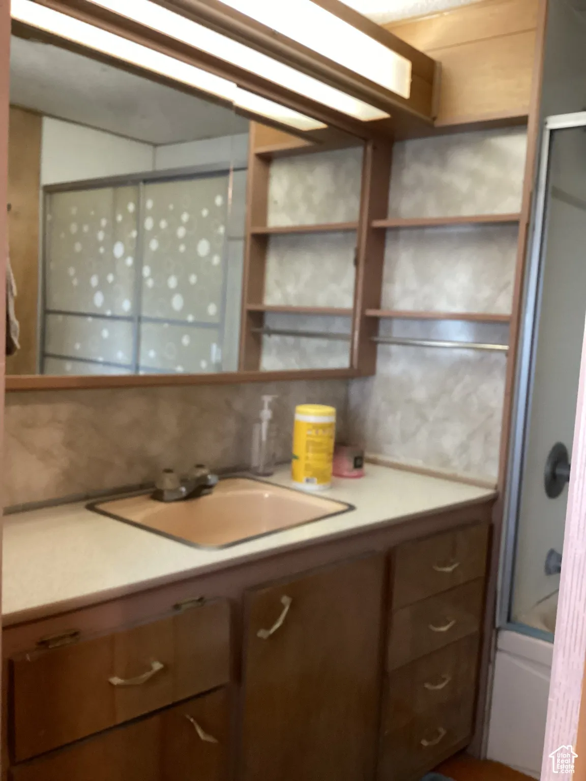 Kitchen featuring a sink, light countertops, open shelves, and backsplash