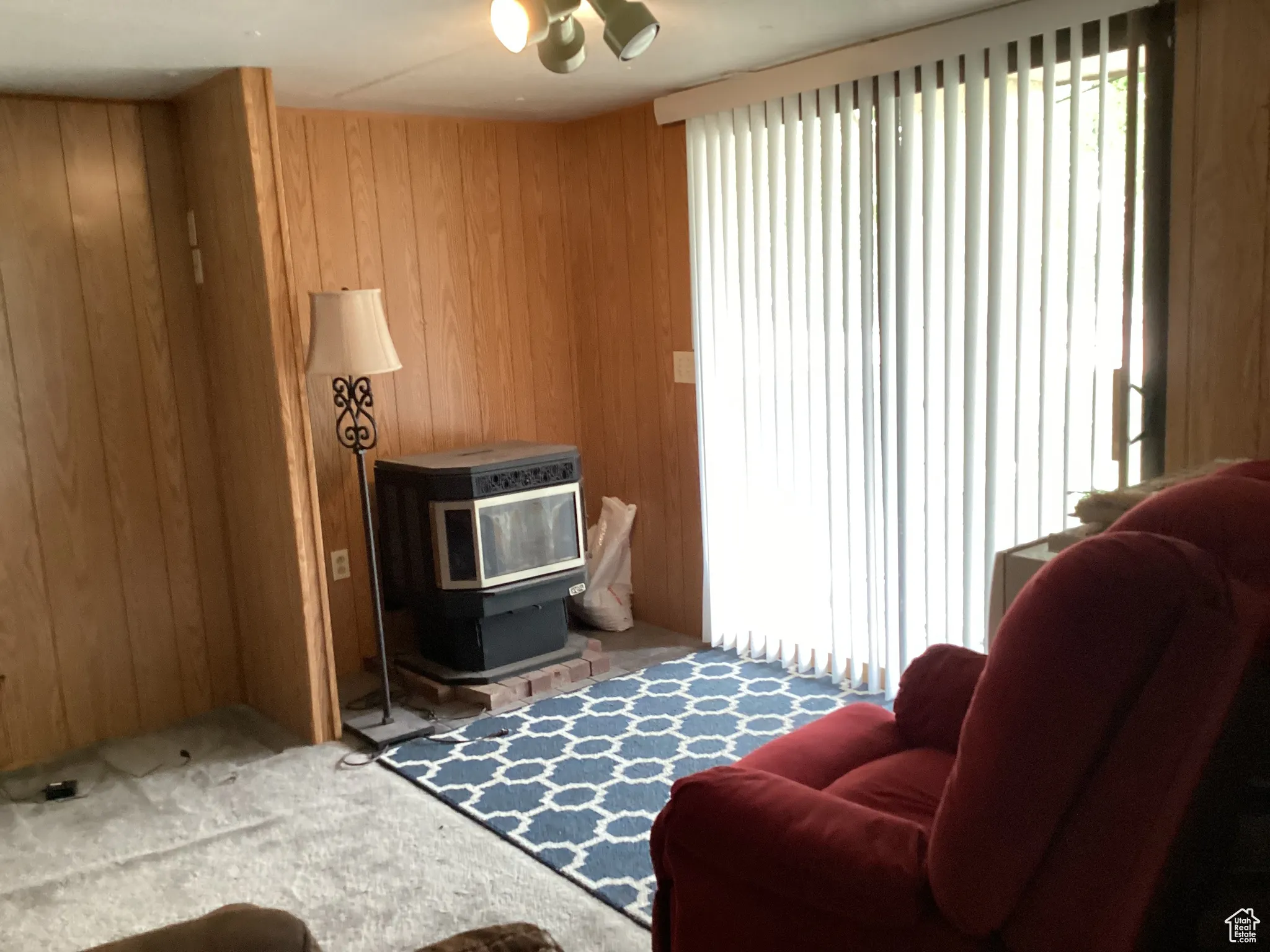 Living area with wooden walls, a wood stove, and carpet