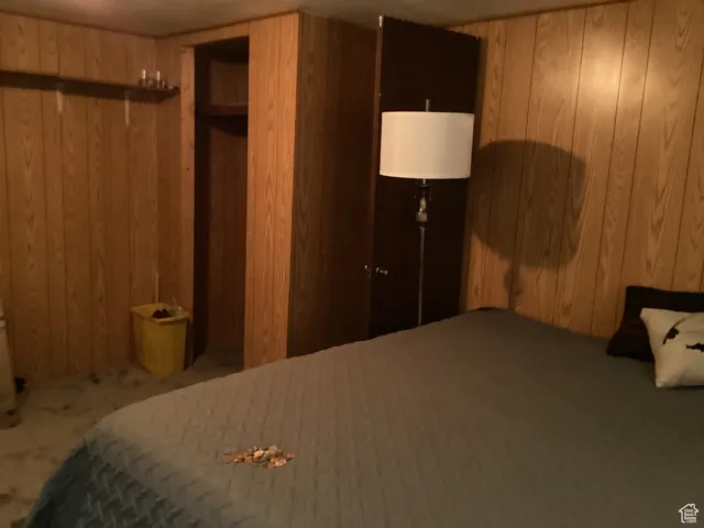 Bedroom featuring wood walls and carpet floors