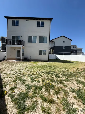Back of house featuring central AC unit, a balcony, and stucco siding
