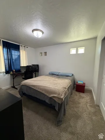 Carpeted bedroom featuring a textured ceiling and baseboards