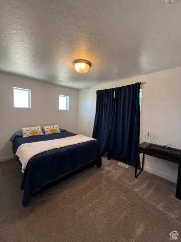 Bedroom with carpet floors, a textured ceiling, and baseboards