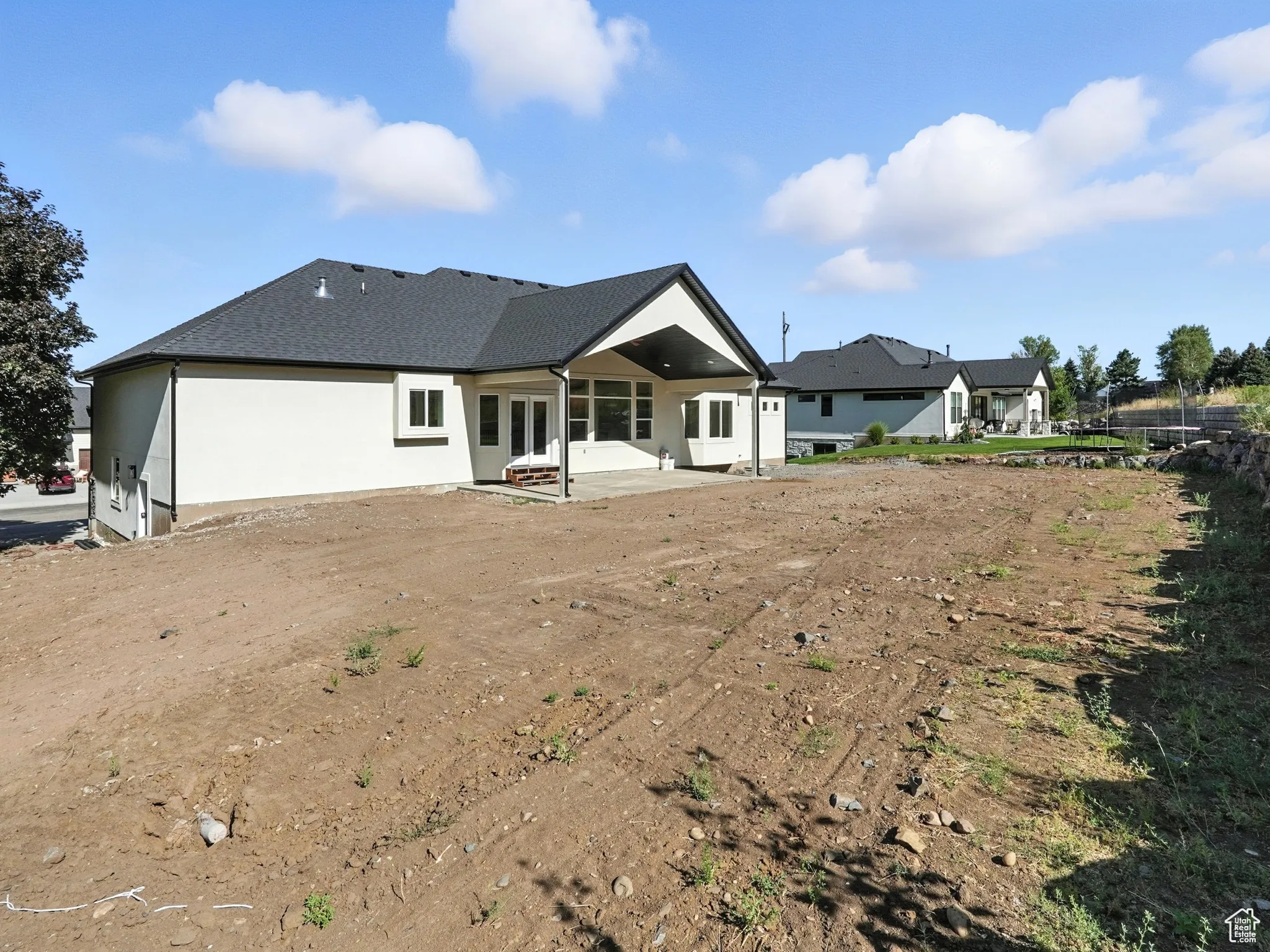 Back of house featuring a patio, a shingled roof, and stucco siding