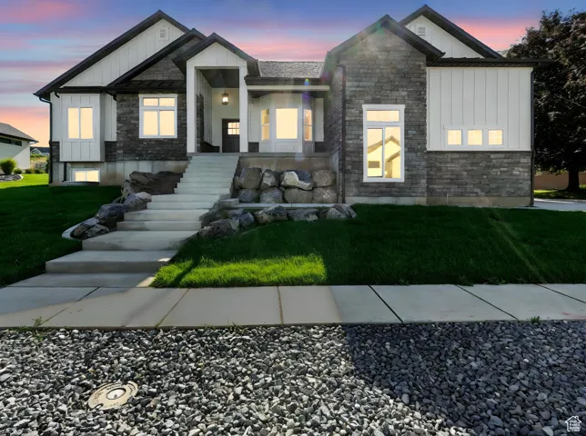 Modern inspired farmhouse featuring board and batten siding, stone siding, and a yard