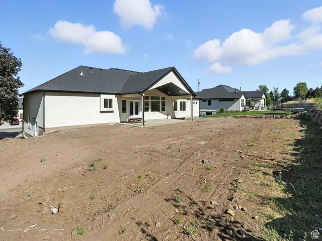 Back of house featuring a patio, a shingled roof, and stucco siding