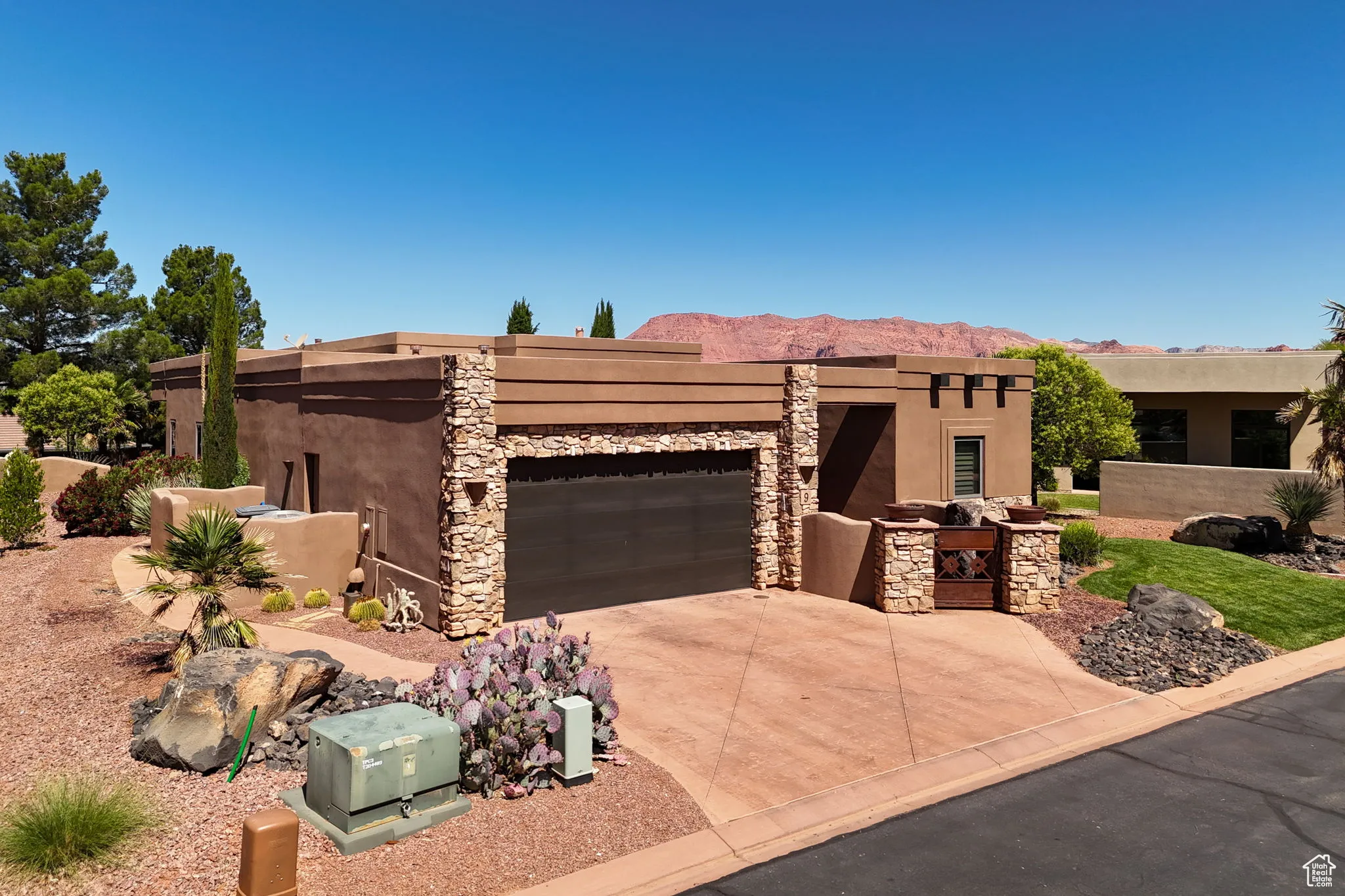 Adobe home featuring a garage, stucco siding, driveway, and a mountain view