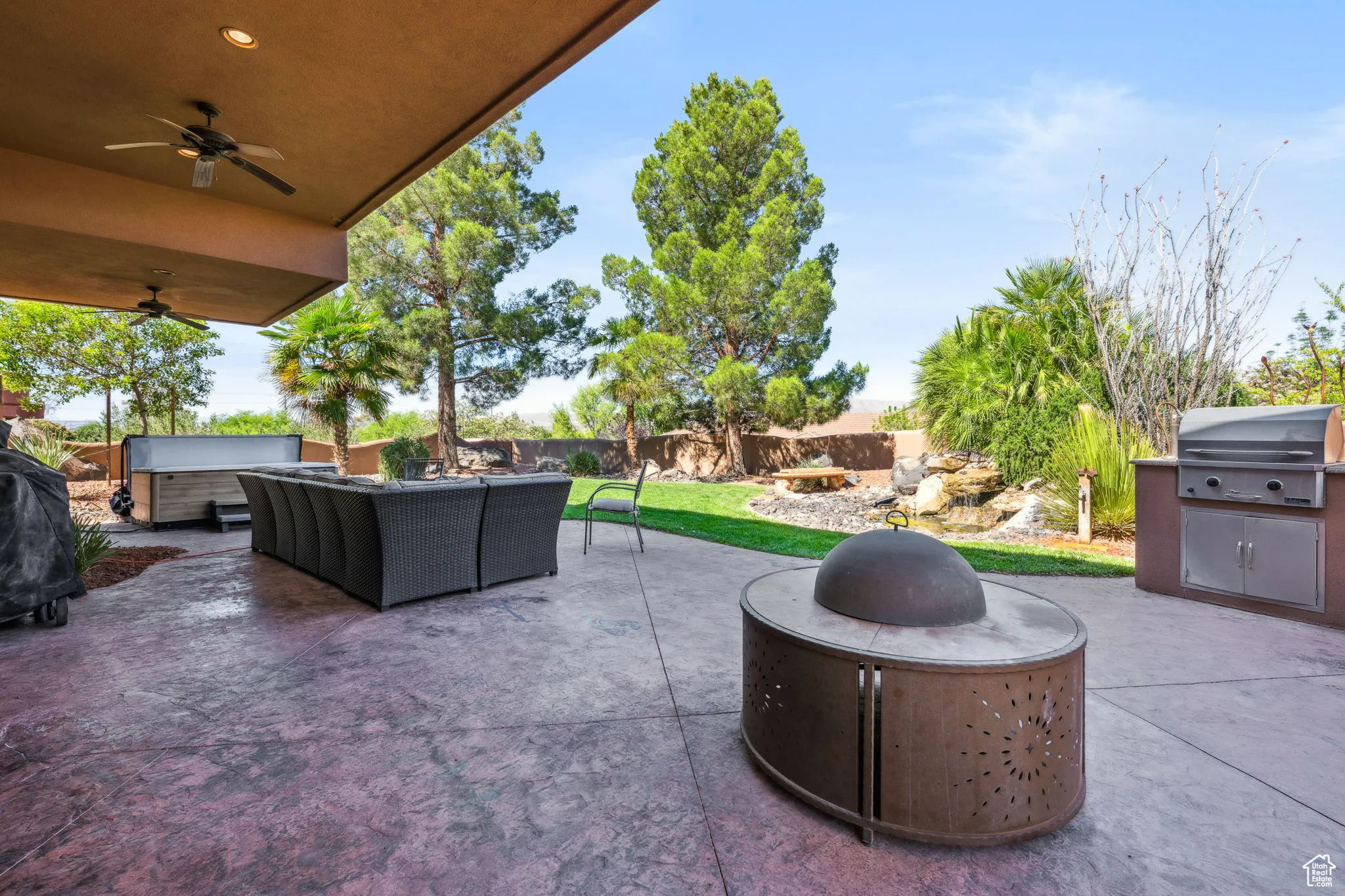 Fenced backyard with area for grilling, a patio area, an outdoor living space with a fire pit, and ceiling fan