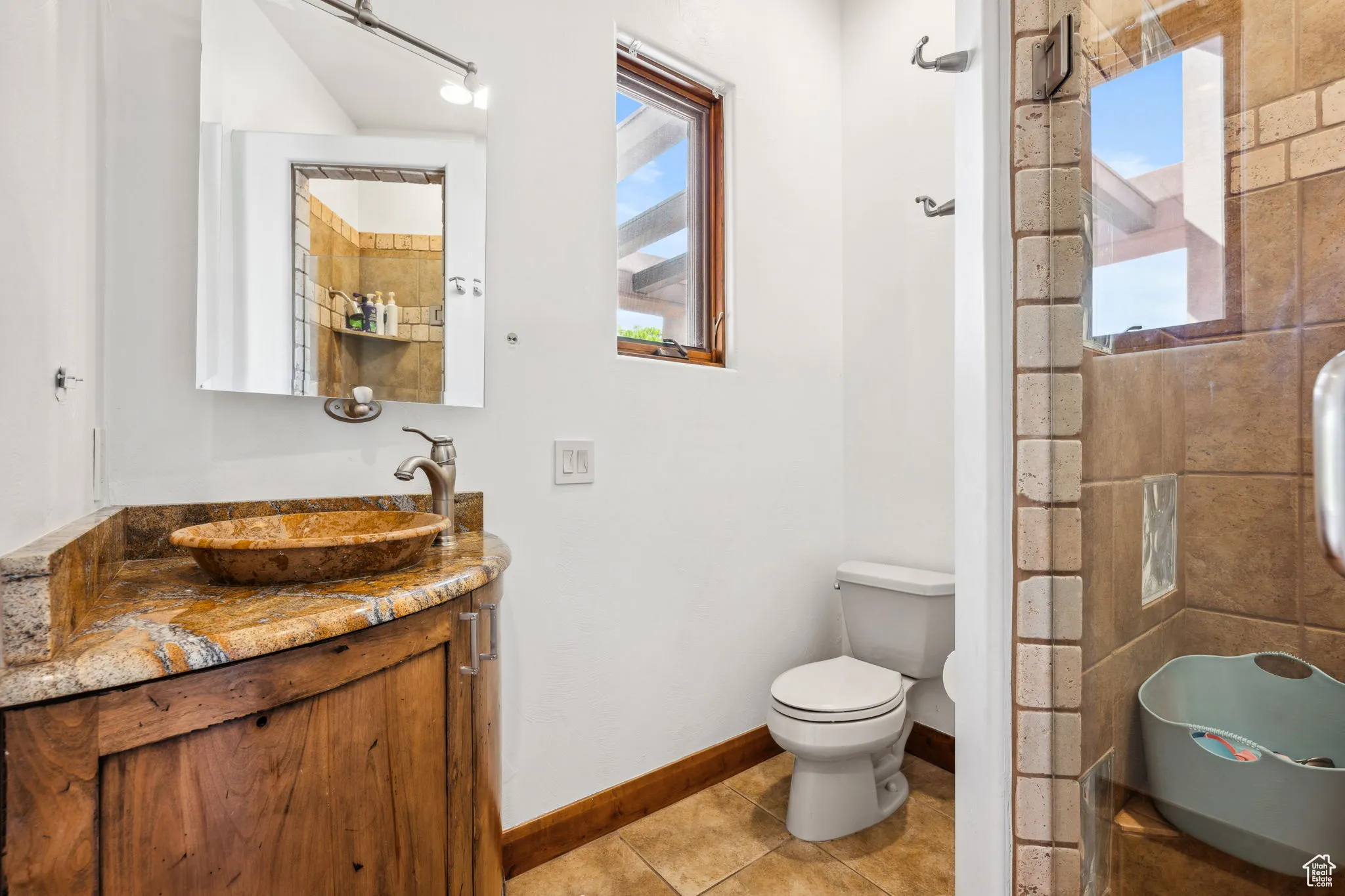 Bathroom featuring plenty of natural light, vanity, toilet, and tile patterned flooring
